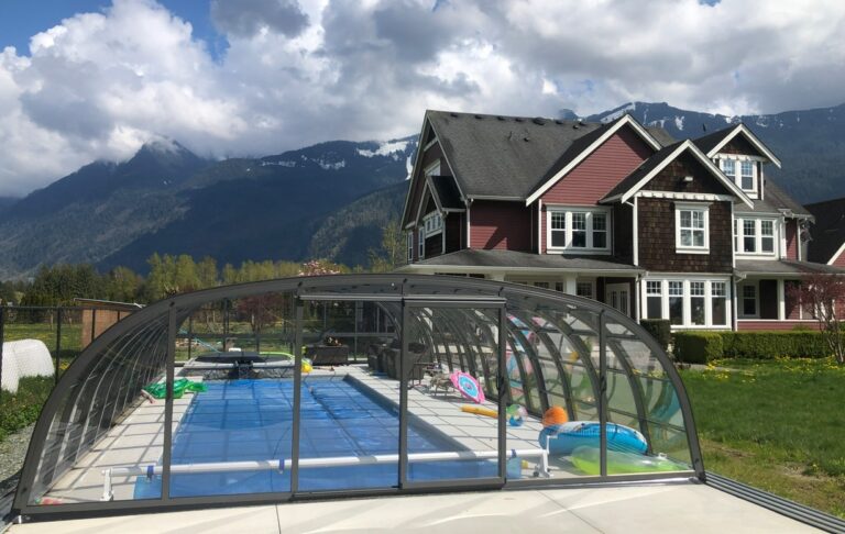 High retractable pool cover over large outdoor pool and deck with pool toys in the background