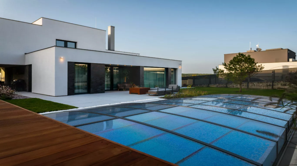 retractable low pool enclosure protecting outdoor pool with a modern home and a tree in the background